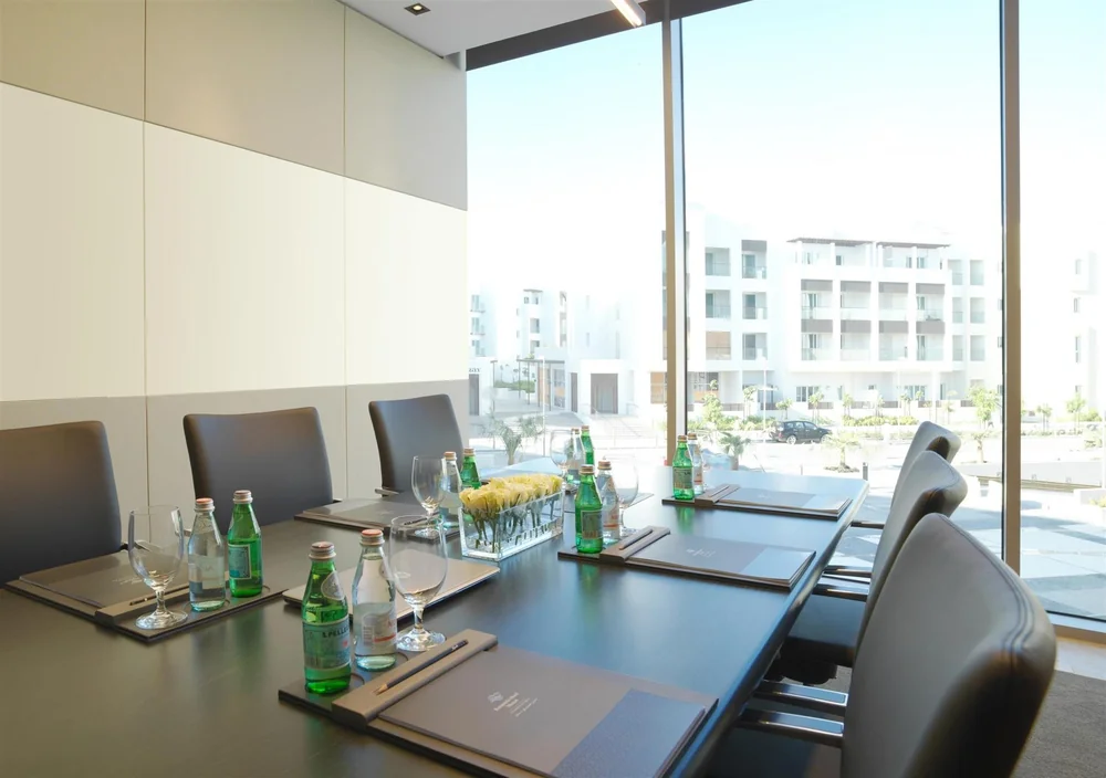 Escena empresarial ilustrativa: mesa de reuniones con cuadernos y lápices en el hotel Kempinski de Mascate, Omán.